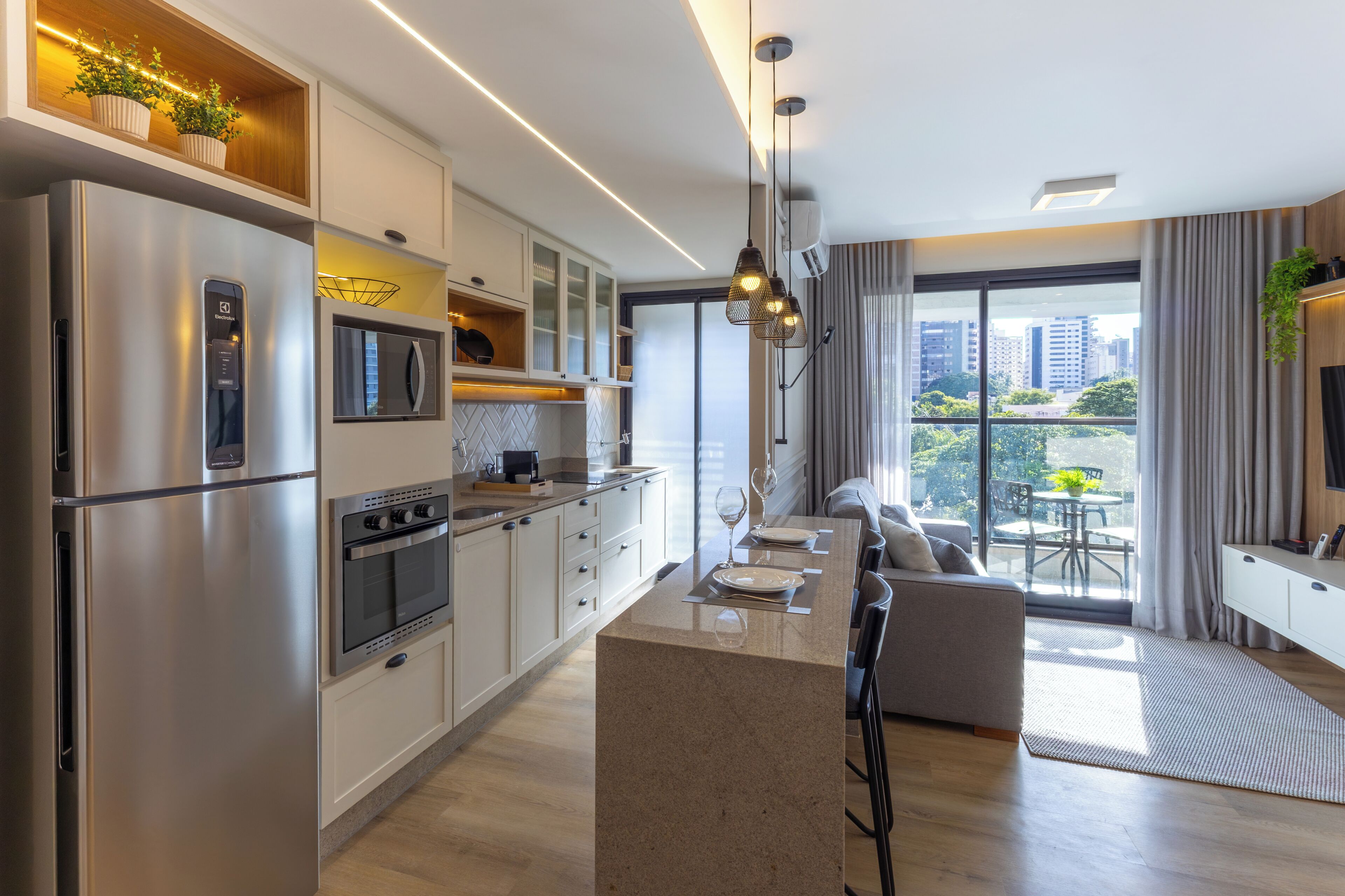 Una cucina moderna con elettrodomestici in acciaio inossidabile, un'area pranzo con tavolo in vetro e vista sulla città attraverso ampie finestre.