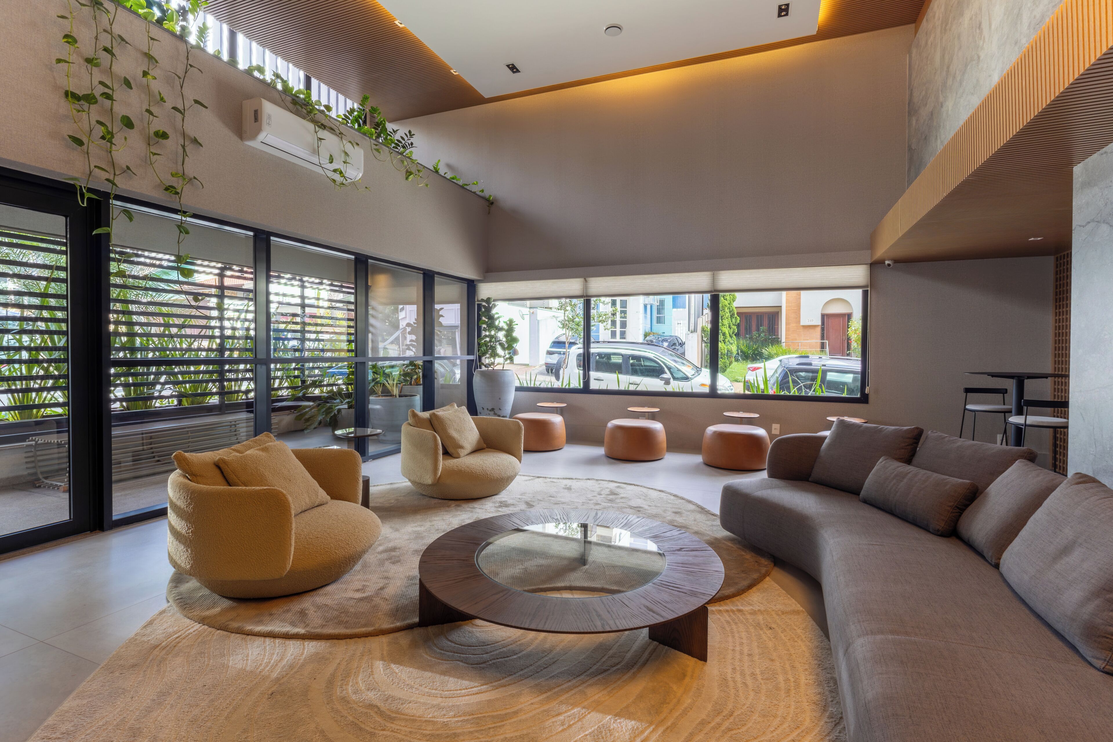 A modern lounge area with a round coffee table, sofas, and a view of the street outside.