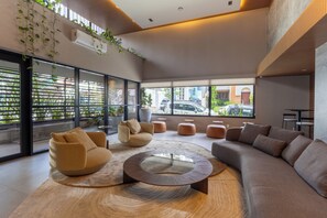 A modern lounge area with a round coffee table, sofas, and a view of the street outside. - Sophisticated Apartment in Cambuí (Campinas)