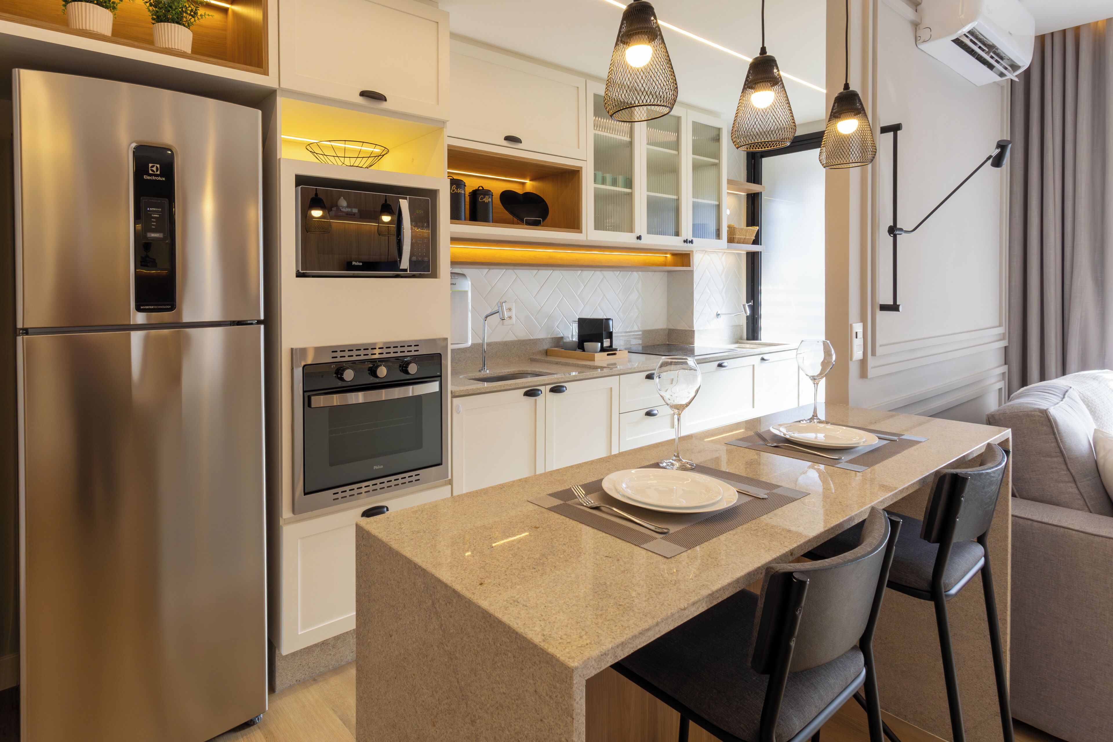 A modern kitchen with a built-in oven, a refrigerator, and a coffee machine.