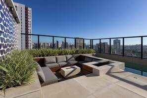 A rooftop terrace with a modern outdoor seating area, a pool, and a city skyline view. - Sophisticated Apartment in Cambuí (Campinas)
