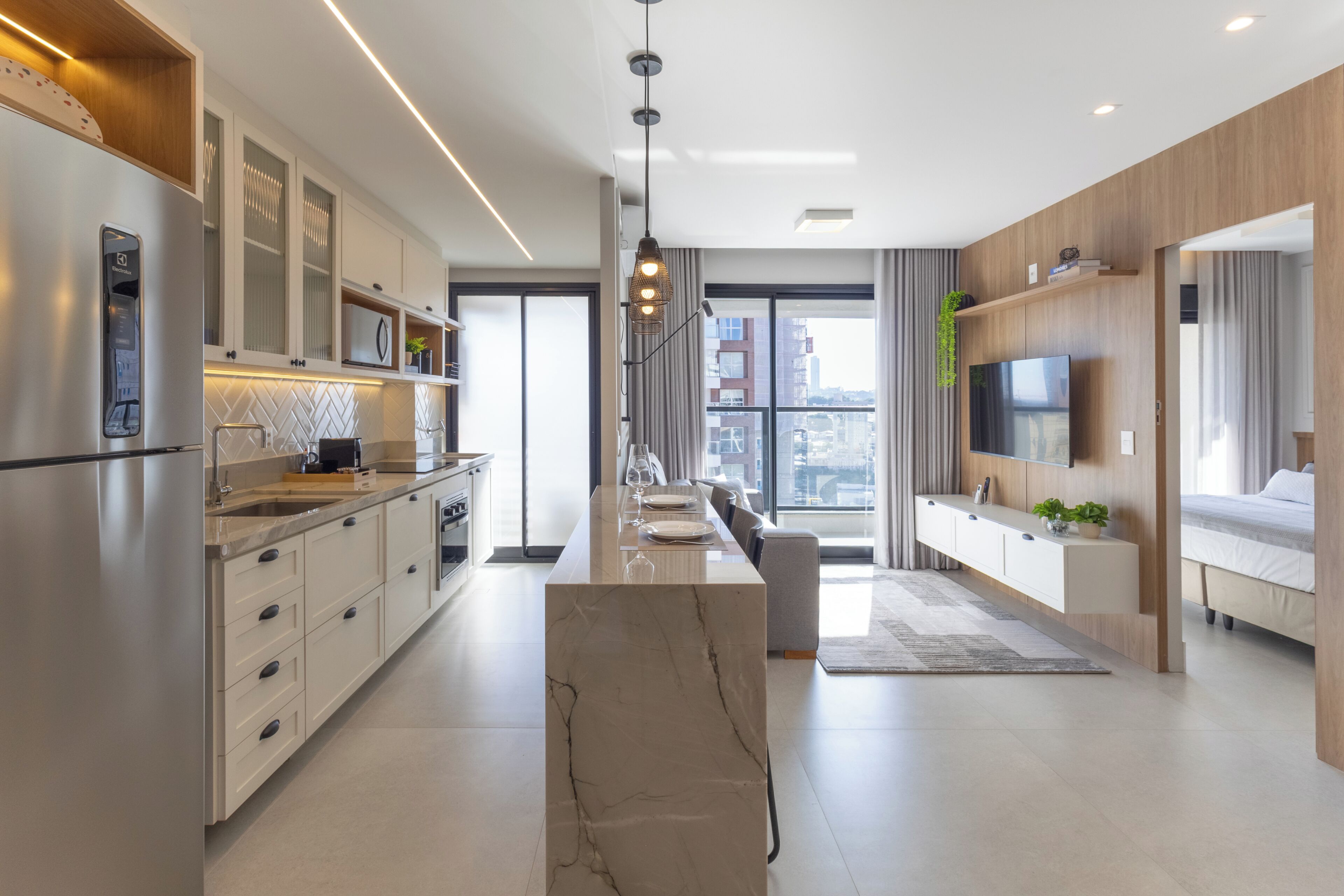 Una cocina moderna con una isla central, electrodomésticos integrados y un amplio ventanal con vistas a la ciudad.