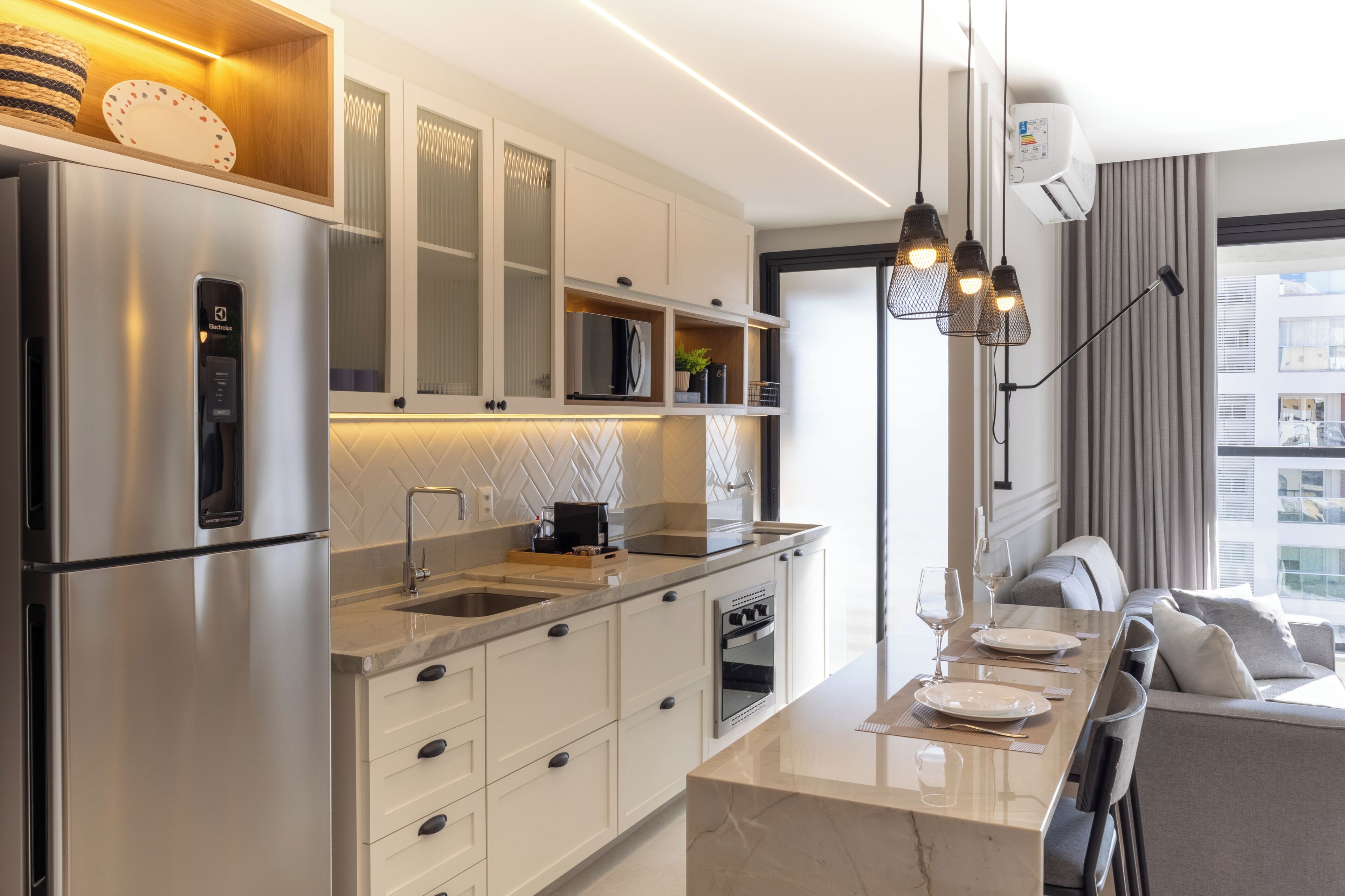 A modern kitchen with stainless steel appliances, a marble countertop, and a dining area with a sofa and table.