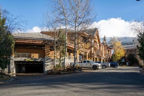 A building with a stone facade, a garage, and parked vehicles. - Whistler Central |Free PKG&Hot Tub,Walk2Everything (Whistler)