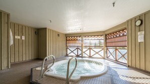 Een bubbelbad in een ruimte met houten wanden en een betegelde vloer.