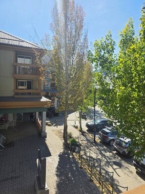 Un bâtiment doté d’un espace extérieur abrité, d’un parking avec des voitures et d’un arbre au premier plan.