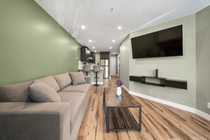 A modern living room with a sofa, a coffee table, and a TV mounted on the wall.