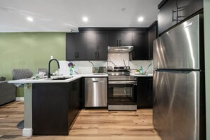 A modern kitchen with dark cabinets, stainless steel appliances, and a marble backsplash.