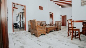 Una habitació amb un sofà de fusta, una taula de dinar amb cadires i un mirall a la paret.