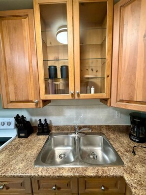 A kitchen with wooden cabinets, a double stainless steel sink, and a stove. - Modern Cozy 2 BR Retreat Near DT & CTrain (Calgary)