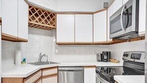 A compact kitchen with white cabinets, a stainless steel dishwasher, a microwave, a toaster, and a stove. - Ocean View Condo in Beachfront Resort Beach, Pool, Gym 607 (Miami)