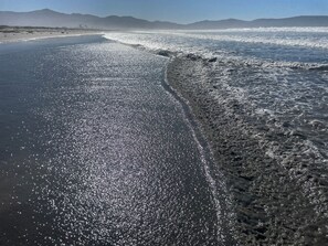 A beach with a clear sky and distant mountains.