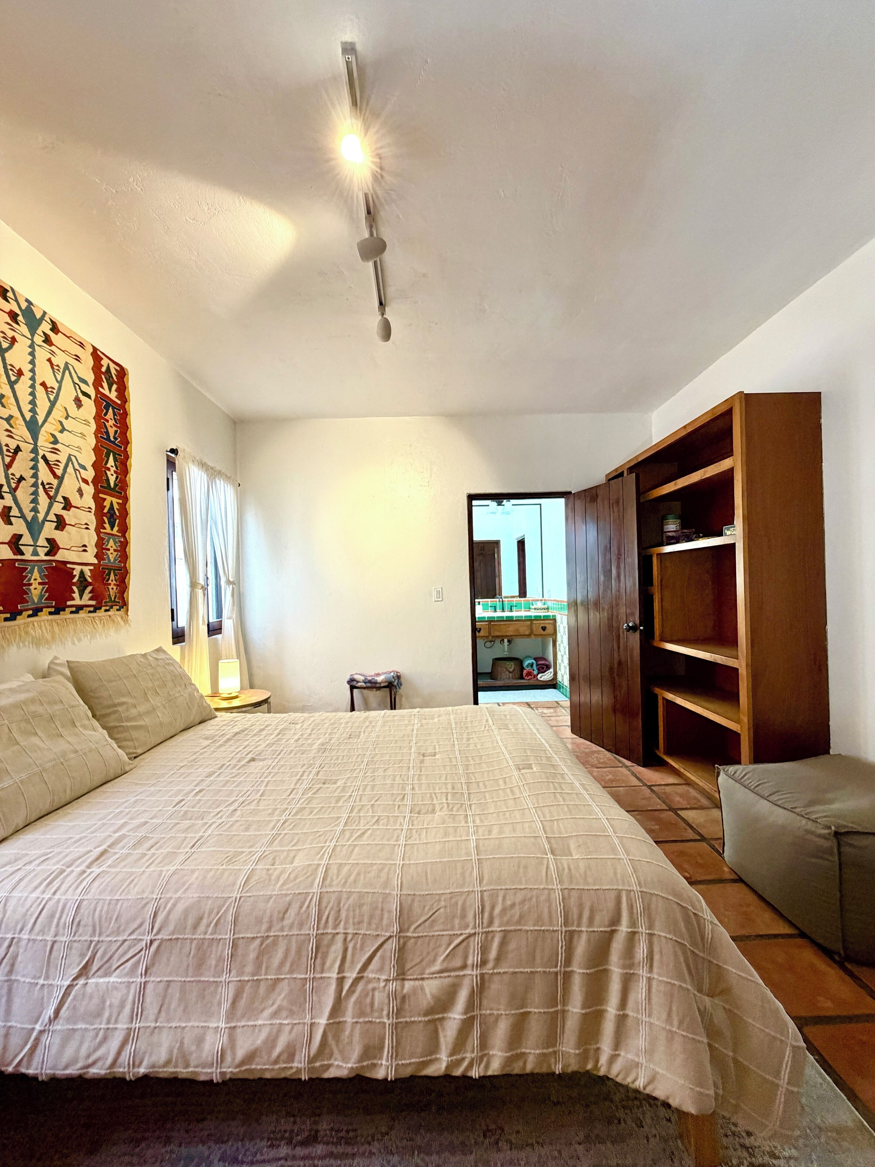 A bedroom with a large bed, a wardrobe, and a small table.