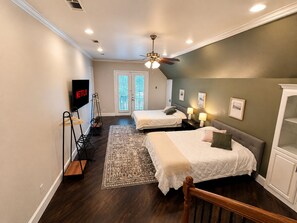 A bedroom with two beds, a ceiling fan, a TV, and a view of the outdoors. - 5BR and 3.5 BA in Lower Greenville Home with Game Room Sleeps 14 (Dallas)