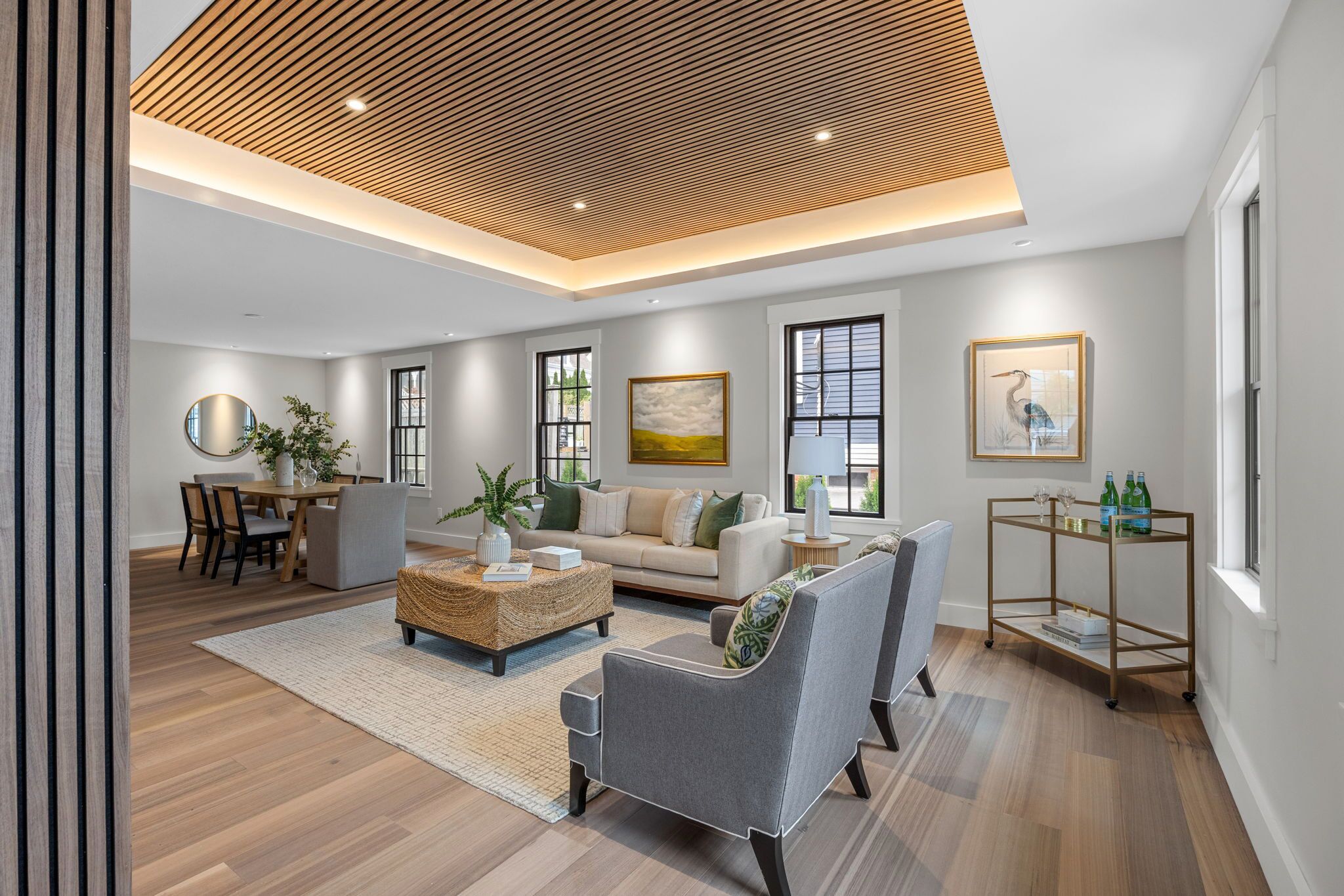 A modern living room with a wooden ceiling, a sofa, a coffee table, and a dining area with chairs and a table.