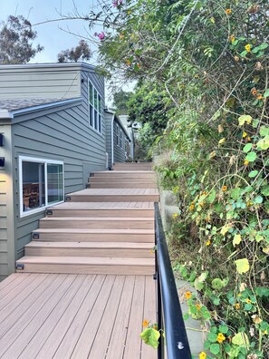 A wooden deck leading to a house with a grey exterior and multiple windows. - Newly Remodeled Luxe Canyon Studio Hideaway (San Diego)