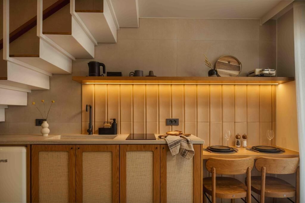 Une cuisine moderne dotée d’un plan de travail en bois, de placards intégrés et d’une étagère murale où sont rangés les ustensiles de cuisine.