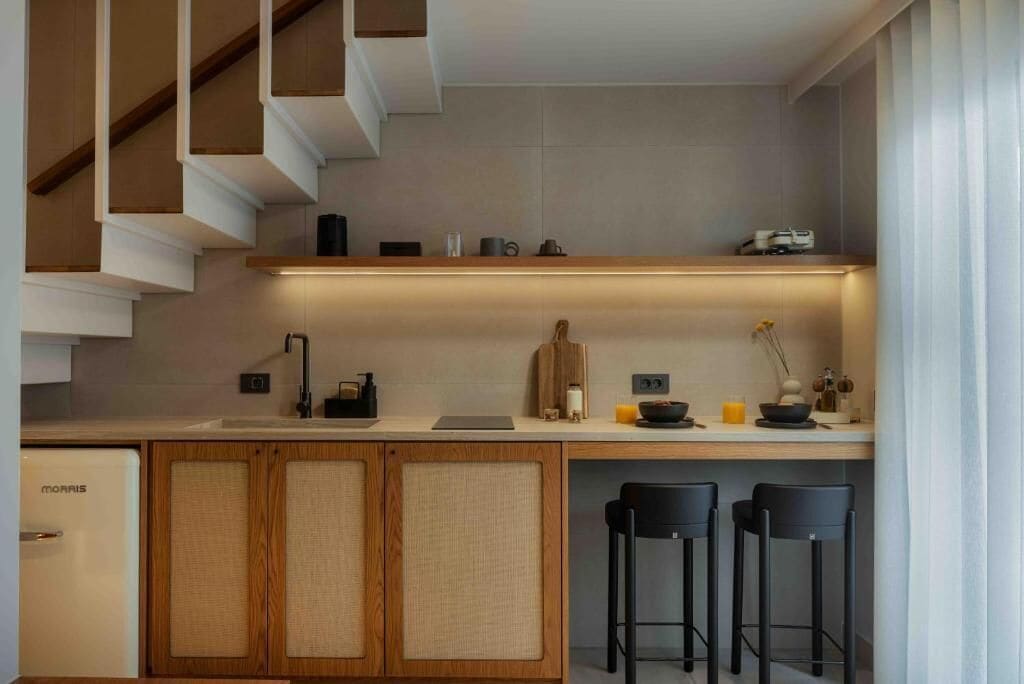 Eine moderne Küche mit integriertem Kühlschrank, Holzschränken, einer Bar und einer Treppe.