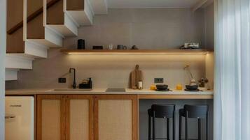 Eine moderne Küche mit integriertem Kühlschrank, Holzschränken, einer Bar und einer Treppe.