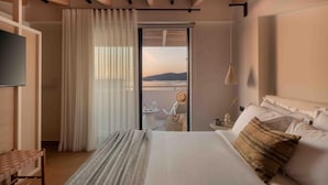Ein Hotelzimmer mit Bett, Fernseher, Fenster mit Vorhängen und Blick ins Freie.
