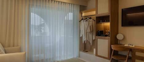 A hotel room with a bed, a desk, a chair, a TV, and a wardrobe.