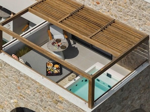 Terraza en la azotea con hidromasaje, zona de estar y pared de piedra.