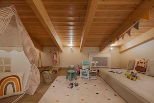 Un salón infantil acogedor con techo de madera, un sofá, una mesita y juguetes.