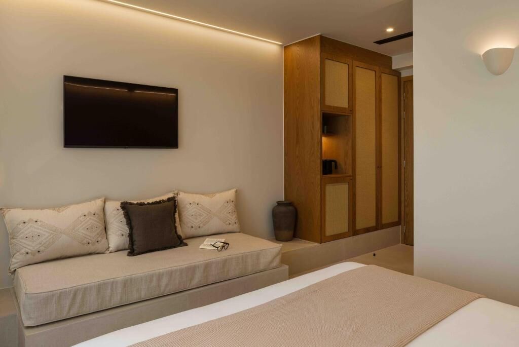 A modern bedroom with a bed, a sofa, a television, and a wardrobe.