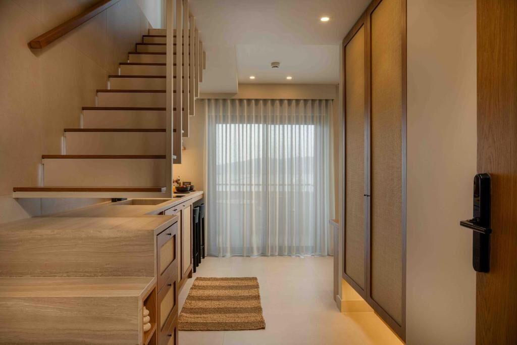 A modern interior with a wooden staircase, a kitchen area, and a sliding door.