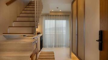 A modern interior with a wooden staircase, a kitchen area, and a sliding door.