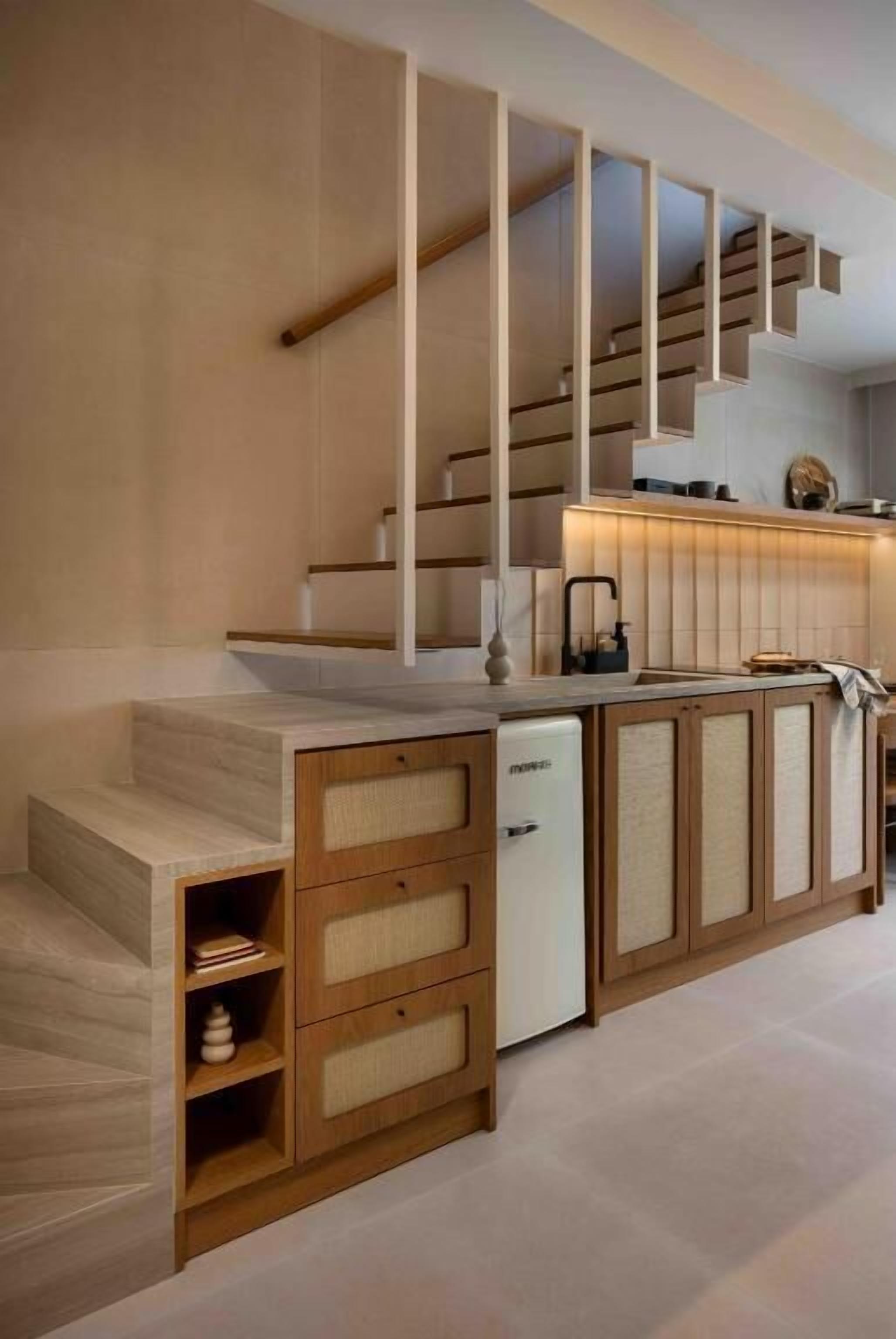 A modern kitchen with a built-in dishwasher, wooden cabinetry, and a staircase leading to an upper level.