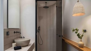 Ein modernes Badezimmer mit einem großzügigen Waschtisch, einer Dusche und einer Pendelleuchte.
