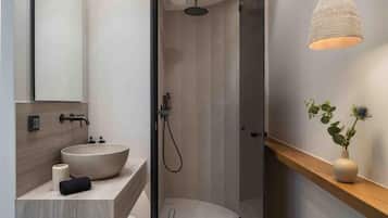 A modern bathroom with a large vessel sink, a shower, and a hanging light fixture.