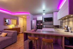 A modern kitchen with a central island, bar stools, a microwave, and a refrigerator. - Perlesia, a cocoon designed just for you. (Le Gosier)