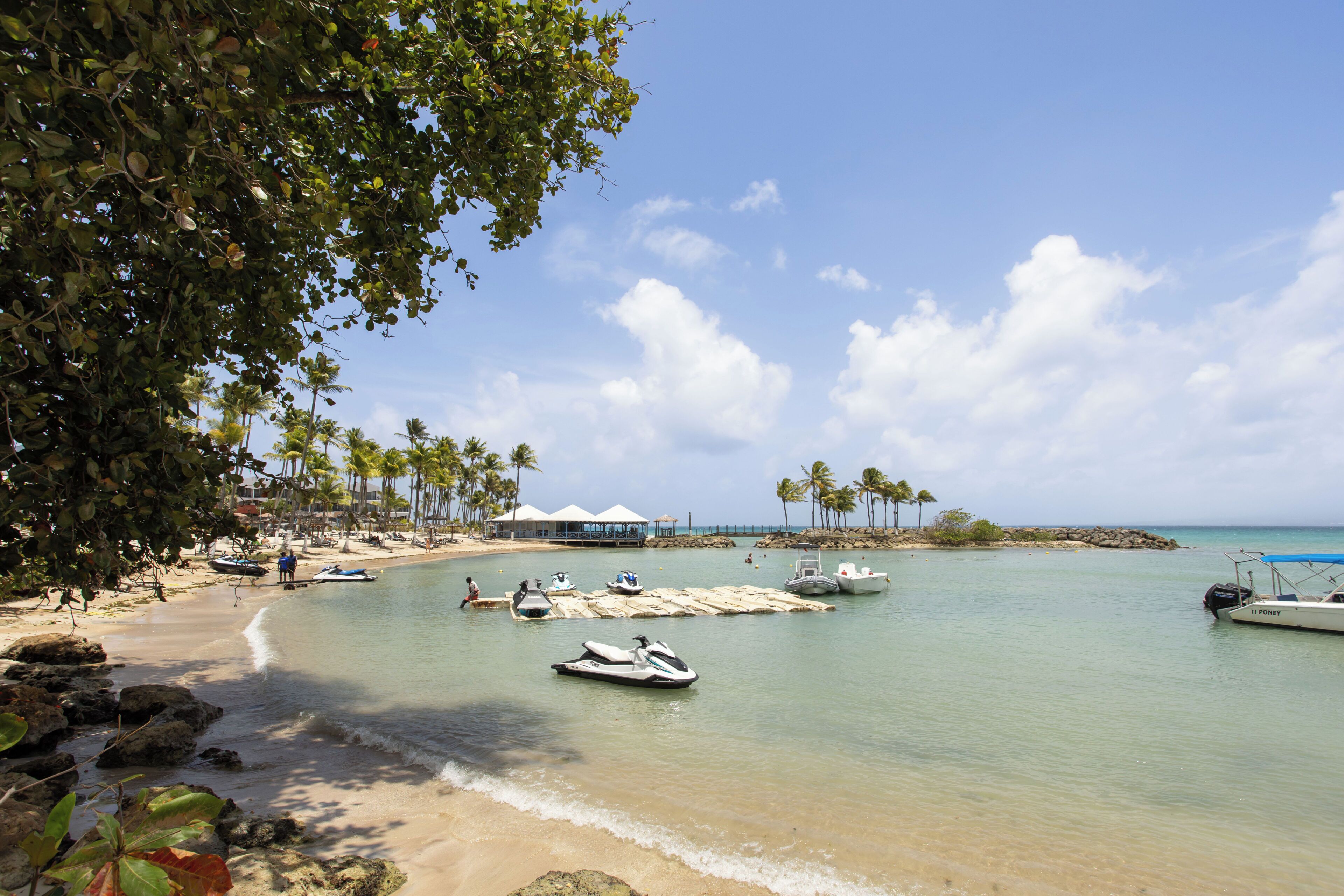 Une plage aux eaux cristallines, avec des bateaux et des palmiers.