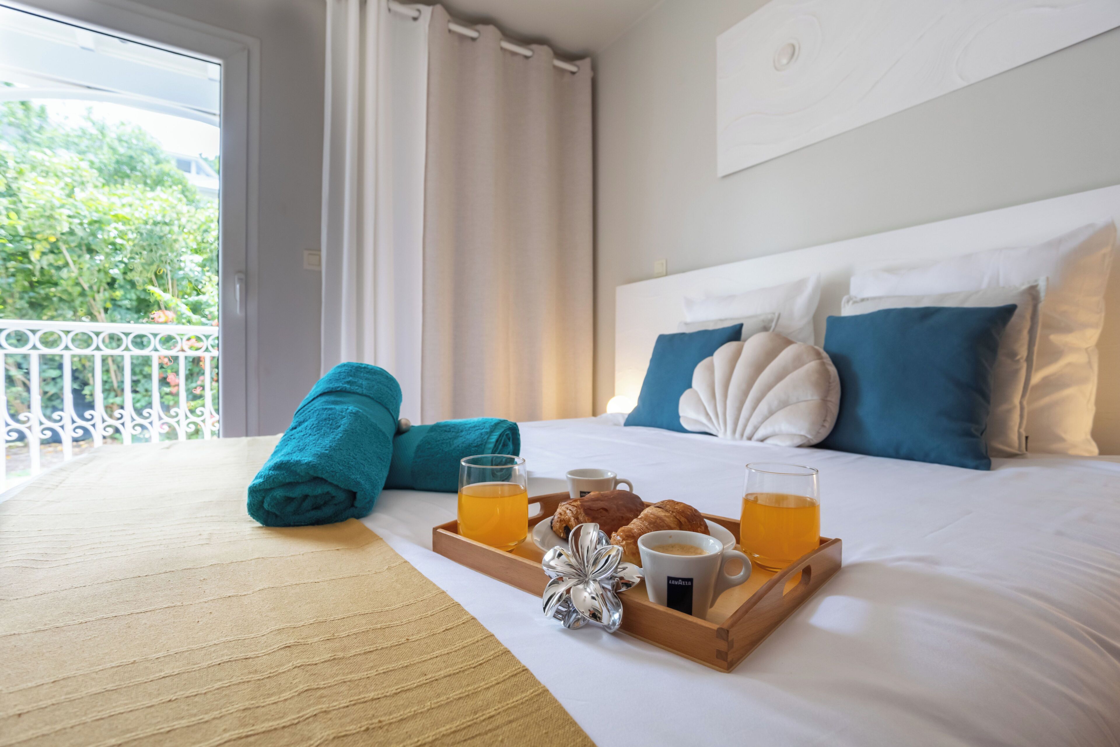 Ein Hotelzimmer mit einem Bett, einem Frühstückswagen mit Croissants, einem Glas Orangensaft und einer Tasse Kaffee.