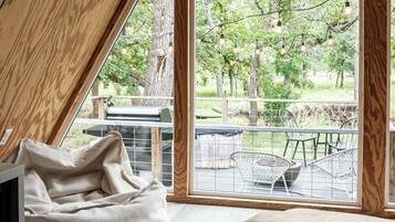 Une pièce avec un plafond en pente, une grande fenêtre et une vue sur les arbres et un espace patio.