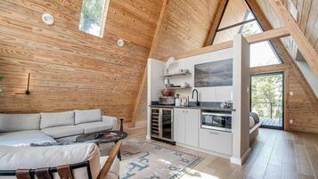 Un espace de vie chaleureux de style loft, avec un intérieur en bois, un canapé, une table basse et un coin cuisine équipé d’appareils électroménagers.