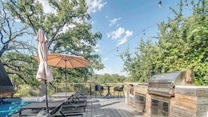 A deck with lounge chairs, a barbecue grill, and a pool. - A-Frame Ranch: Post Oak Treehouse with Shared Pool (Fredericksburg)