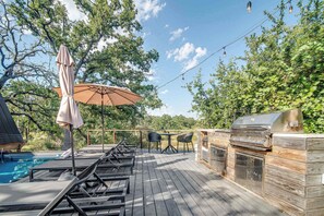Eine Terrasse mit Liegestühlen, einem Grill und einem Pool.