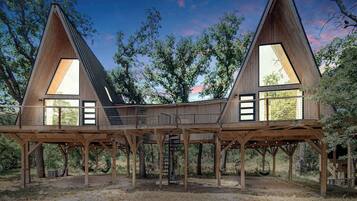Une cabane en bois avec deux toits triangulaires et de grandes fenêtres.