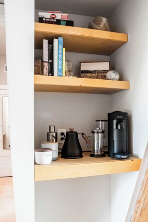 A shelf with books, a coffee maker, and a kettle. - A-Frame Ranch: Post Oak Treehouse with Shared Pool (Fredericksburg)