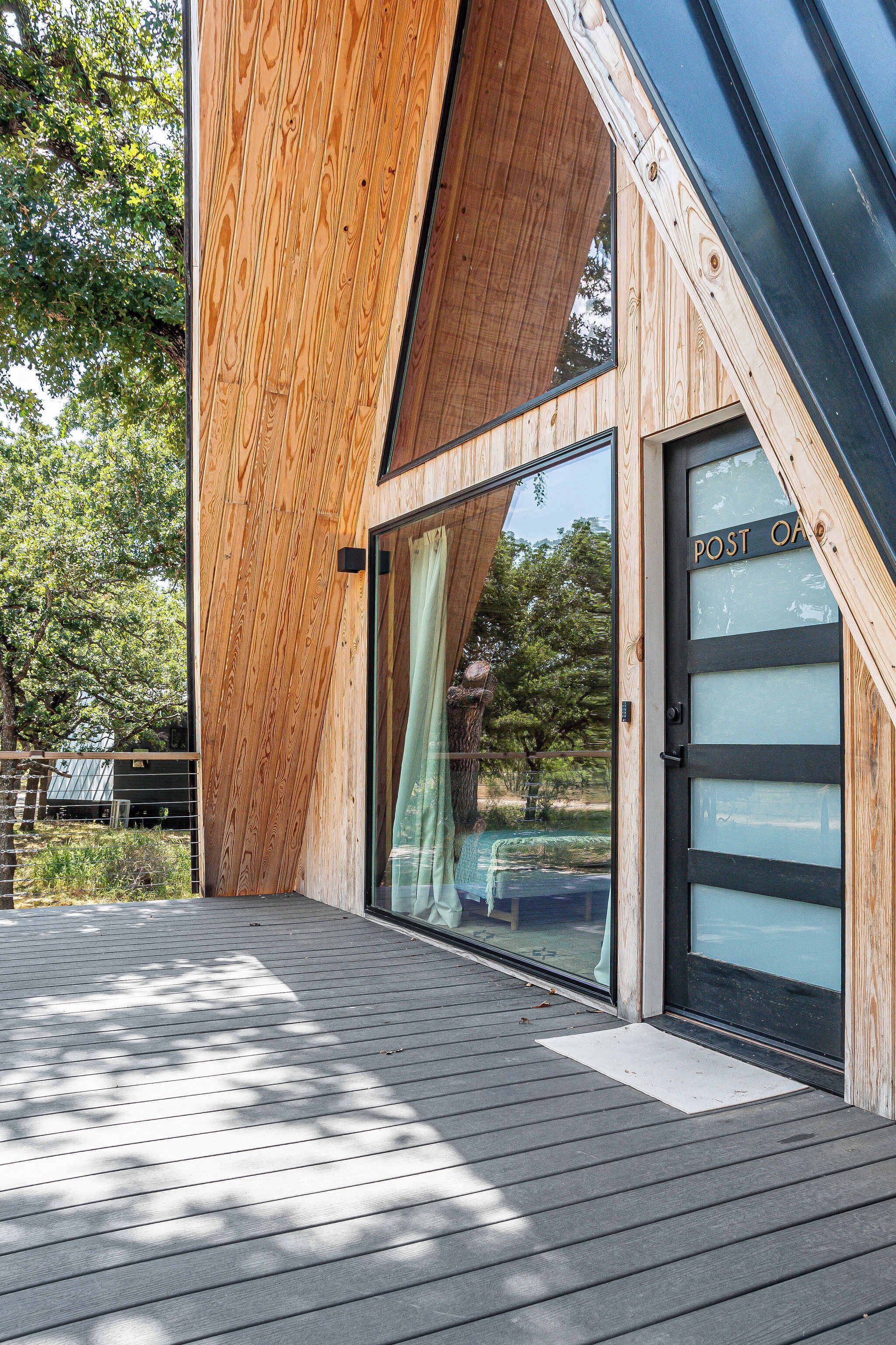 Un bâtiment moderne en bois, doté d’un toit en pente, de grandes fenêtres en verre et d’une terrasse.