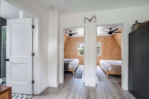 Ein Flur, der zu zwei Schlafzimmern mit Holzwänden und Deckenventilatoren führt.
