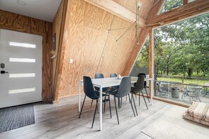 Ein moderner Essbereich mit einer Wand in Holzoptik, einem großen Fenster mit Blick ins Freie und einem Tisch, gedeckt für sechs Personen.