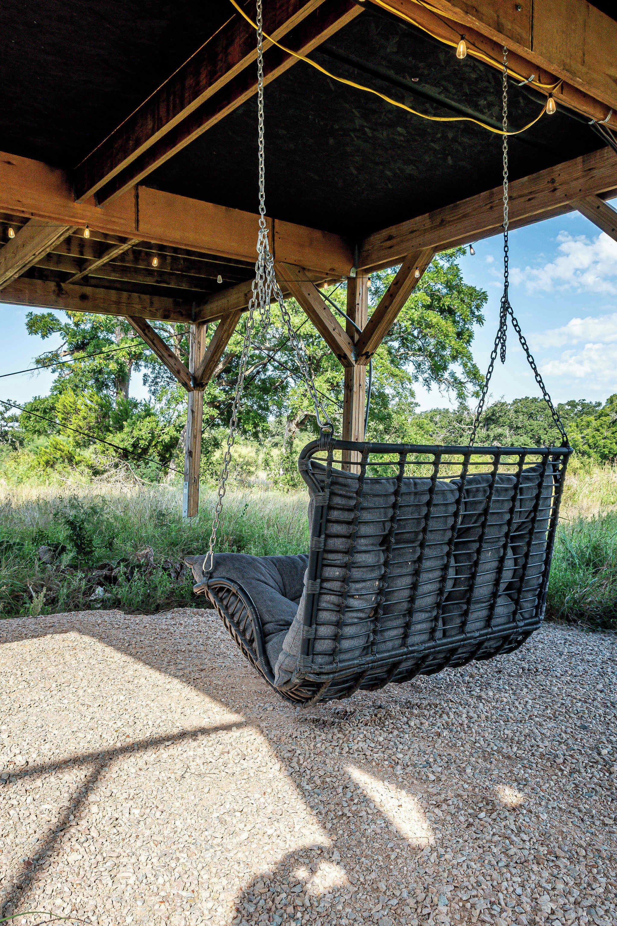 A wooden pergola with a hanging swing chair.