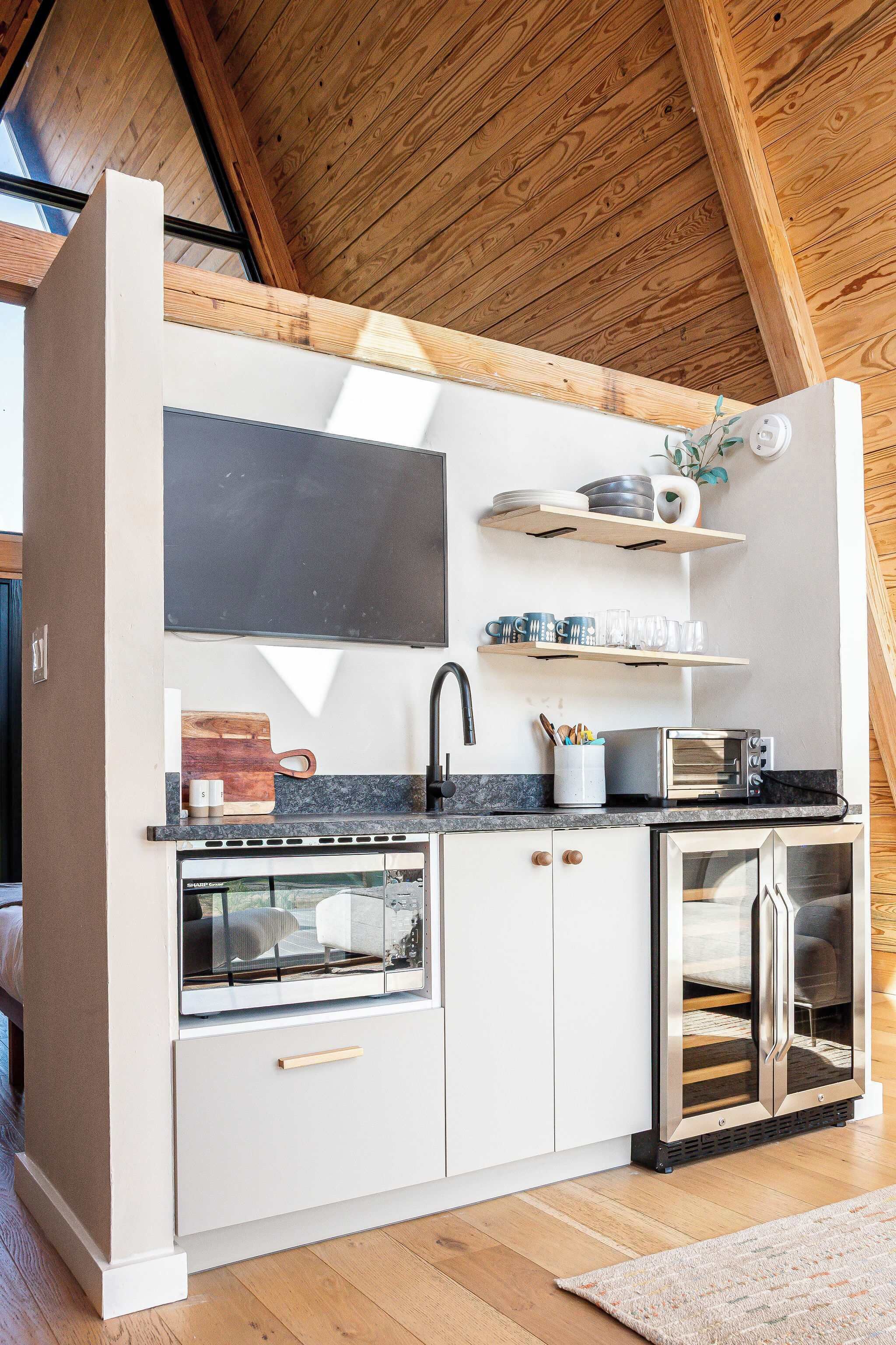 A compact kitchen with white cabinetry, a built-in oven, a microwave, and a toaster.