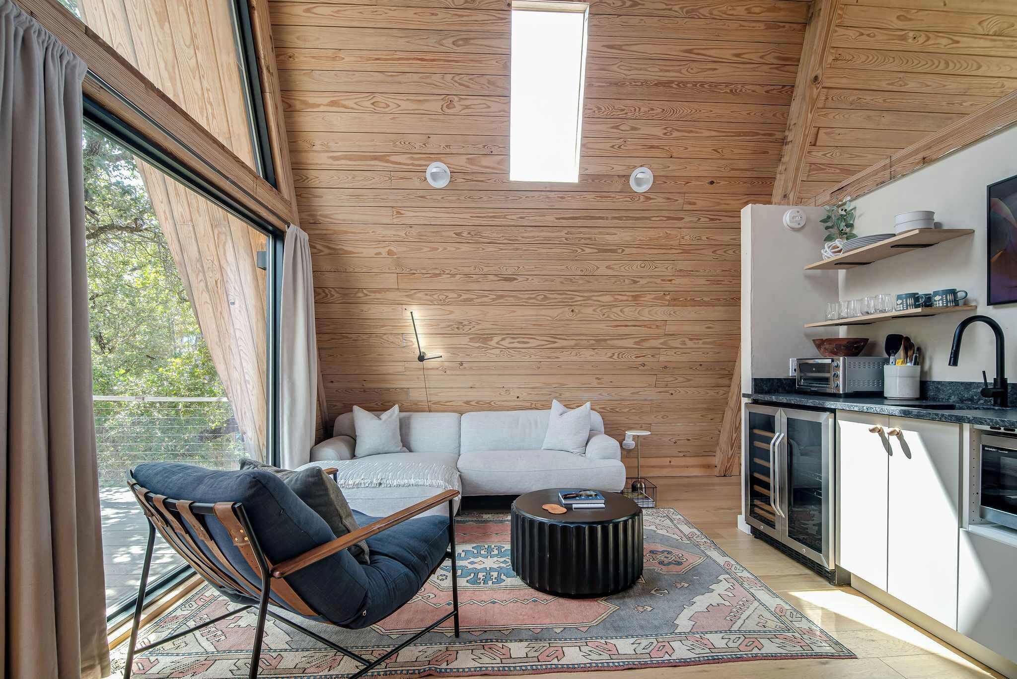 A modern interior with a wooden ceiling, a sofa, a coffee table, and a kitchen area with cabinets and a countertop.