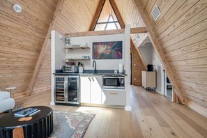 A modern kitchen with a central island, built-in appliances, and a large window above the sink. - A-Frame Ranch: Mesquite Treehouse with Shared Pool (Fredericksburg)