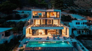 A modern two-story house with a swimming pool, outdoor seating, and a view of the surrounding landscape. - Villa Aurea Beachfront & Spa with Heated Pool (Mimice)